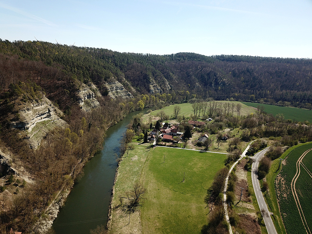 NSG 24, Blick von Nordwesten über die Werra auf die Nordmannssteine und hinten rechts daran anschließend das Klosterholz im NSG „Klosterholz und Nordmannssteine“ (Wartburgkreis). In der Bildmitte: Siedlung Ebenau (Gemeinde Amt Creuzburg). (Foto: Holm Wenzel, 16.04.2022).