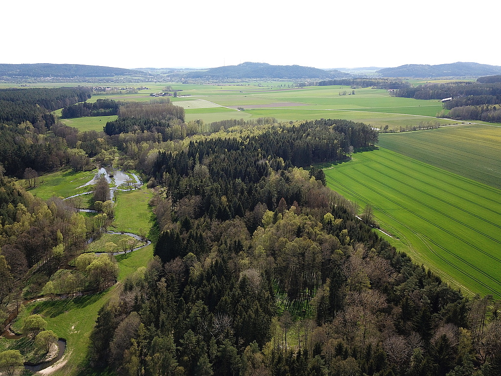 NSG 249, Blick von Nordosten auf den südlichsten Teil des NSG „Föritzgrund“ mit renaturierter Föritz und Anteil im ehemaligen Grenzstreifen (quer in der Bildmitte verlaufend), hier in den Gemarkungen Sichelreuth und Rotheul (Landkreis Sonneberg). Blick Richtung Schwärzdorf bei Mitwitz (Landkreis Kronach) und dahinter Wörlsdorf bei Sonnefeld (Landkreis Coburg) in Bayern, rechts hinten: Fürth a. Berg bei Neustadt b. Coburg. (Foto: Holm Wenzel, 09.05.2021)