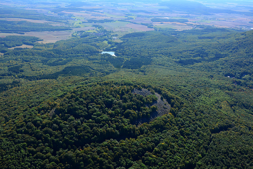 NSG 349, Blick von Nordwesten auf den Gipfel des Kleinen Gleichberges mit der Steinsburg mit Basaltblockmeer im NSG "Gleichberge". Dahinter: Talsperre Roth II ("An der oberen Milz") und der Ort Roth, rechts: Nordwestseite des Großen Gleichberges und zwischen den beiden Gleichbergen die Siedlung Waldhaus. (Foto: Detlef Stremke/Archiv TLUBN, 22.09.2019)