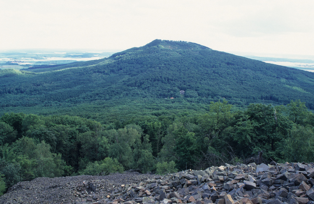 NSG 349, Blick vom Kleinen Gleichberg (mit Basaltblockmeer im Vordergrund) nach Süden auf den Großen Gleichberg östlich von Römhild (Landkreis Hildburghausen). Im Sattel dazwischen in der Bildmitte: Siedlung Waldhaus und Steinsburgmuseum. (Foto: Holm Wenzel, 09.07.1997)
