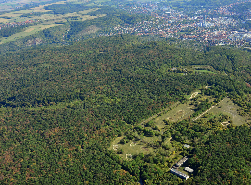 NSG 452, Blick von Südwesten auf den nördlichen Teil des NSG und FFH-Gebietes "Jenaer Forst" (Stadt Jena, Saale-Holzland-Kreis). Vorn außerhalb des FFH-Gebietes und NSG: ehemaliges, jetzt renaturiertes Kasernengelände der Sowjetarmee, dahinter der Otto-Schott-Platz, im Hintergrund rechts: Stadtzentrum Jena, links hinten: Mühltal, Cospeda und Windknollen (NSG Nr. 372). (Foto: Detlef Stremke/Archiv TLUBN, 21.09.2019).