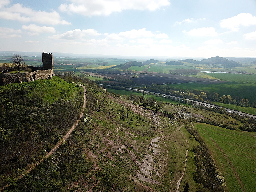 NSG 332, Blick von Nordwesten auf die Südseite des Burgberges der Burg Gleichen (= Wanderslebener Gleiche) mit sogenannten „badlands“ im NSG „Röhnberg“ bei Wandersleben (Landkreis Gotha). Dahinter: die Bundesautobahn A 4 und v. l. n. r.: NSG „Apfelstädter Ried“ (Nr. 61), Längel, Rückberg und im NSG „Wachsenburg“ (Nr. 54) Roter Berg und Bergkegel der Wachsenburg, davor die wassergefüllten ehemaligen Mühlberger Torfstiche im NSG „Schloßleite“ (Nr. 333). (Foto: Holm Wenzel, 30.04.2023)